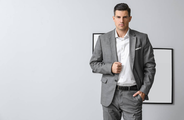 Handsome man in formal suit posing near grey wall - Foto, Bild