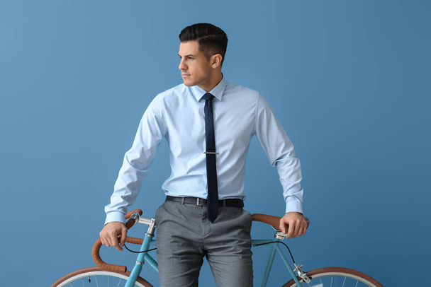 Handsome man in formal clothes with bicycle looking aside near color wall - Фото, зображення