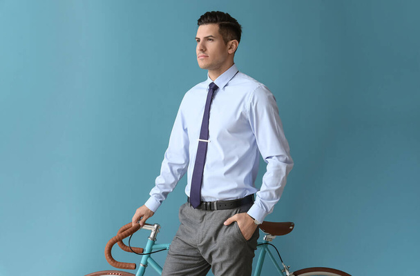 Handsome man in formal clothes with bicycle on color background - Foto, Imagem