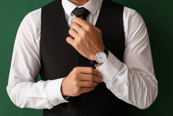 Gentleman in stylish formal clothes adjusting sleeve on color background, closeup - Foto, afbeelding