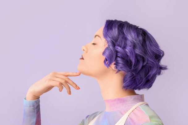 Hermosa mujer joven con pelo violeta sobre fondo de color. Muy Peri - el color del año 2022 - Foto, imagen