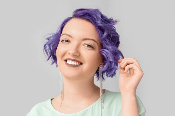 Beautiful young woman with violet hair on light background. Very Peri - color of year 2022 - Zdjęcie, obraz