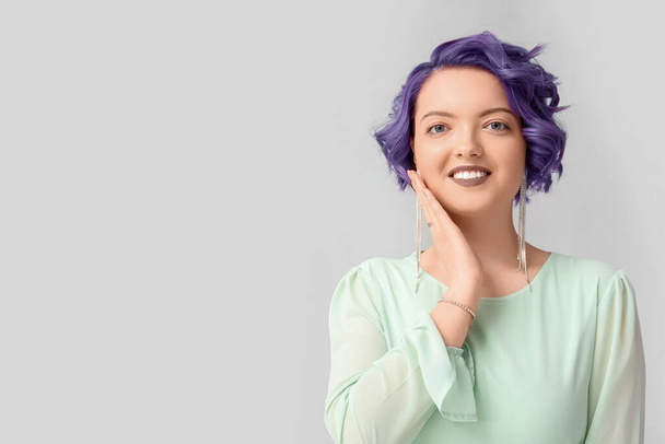 Kaunis nuori nainen, jolla on violetti tukka kevyellä taustalla. Erittäin Peri - väri vuoden 2022 - Valokuva, kuva
