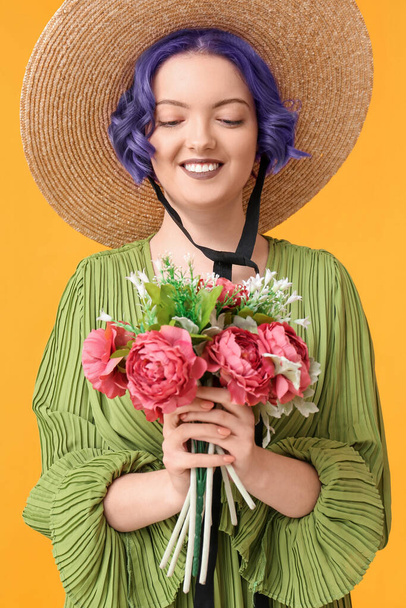 Piękna młoda kobieta z fioletowymi włosami i bukiet kwiatów na żółtym tle. Bardzo Peri - kolor roku 2022 - Zdjęcie, obraz
