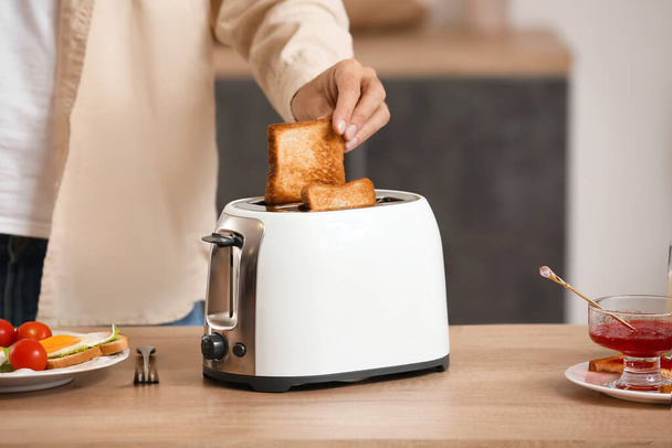 Young man making tasty toasts in kitchen, closeup - Fotó, kép