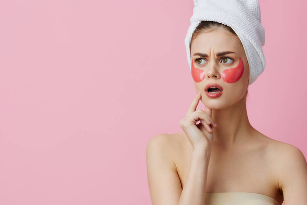 hermosa mujer parches de color rosa en la cara con una toalla en la cabeza fondo aislado - Foto, imagen
