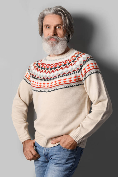 Красивый мужчина в вязаном свитере на сером фоне - Фото, изображение