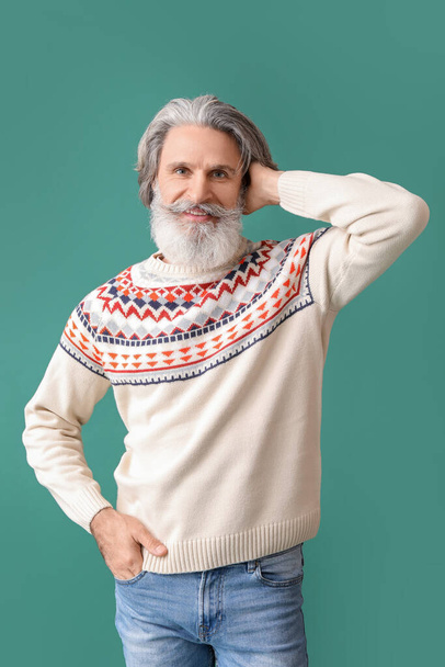 Handsome senior man in knitted sweater on green background - Foto, Imagen