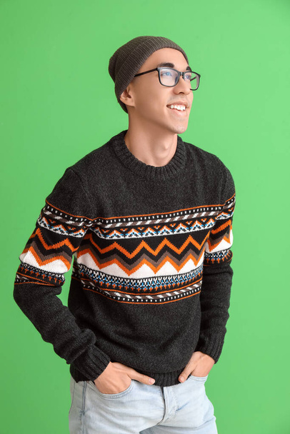 Beau jeune homme asiatique en pull tricoté sur fond vert - Photo, image