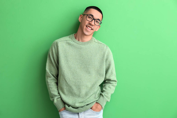 Handsome young Asian man in knitted sweater on green background - Foto, Bild