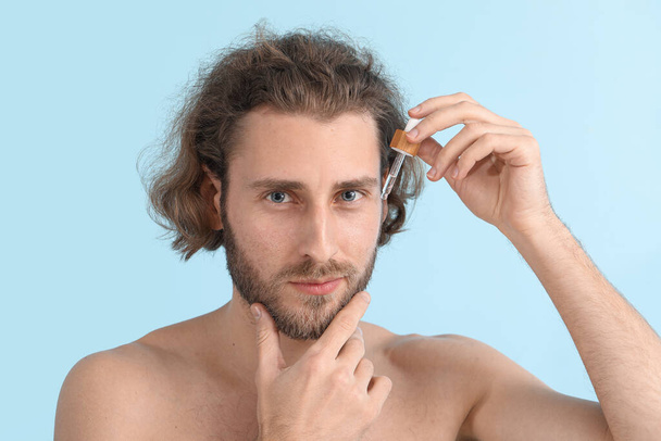 Young man with serum for skin care on color background - Fotografie, Obrázek