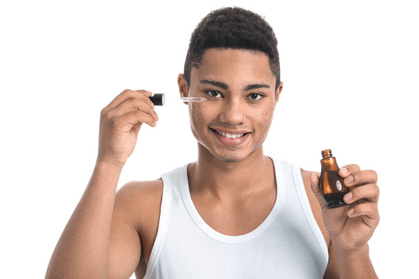 Молодий афроамериканець з сироваткою для догляду за шкірою на білому тлі - Фото, зображення