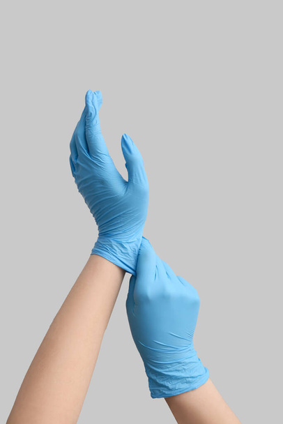 Woman in medical gloves on light background - Photo, Image