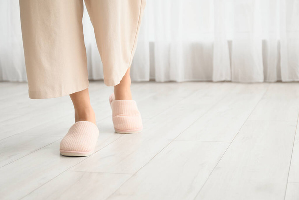 Jonge vrouw in zachte comfortabele slippers thuis - Foto, afbeelding