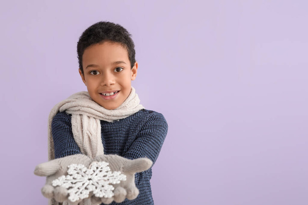 Leuke kleine Afro-Amerikaanse jongen in de winter kleding en met sneeuwvlok op kleur achtergrond - Foto, afbeelding
