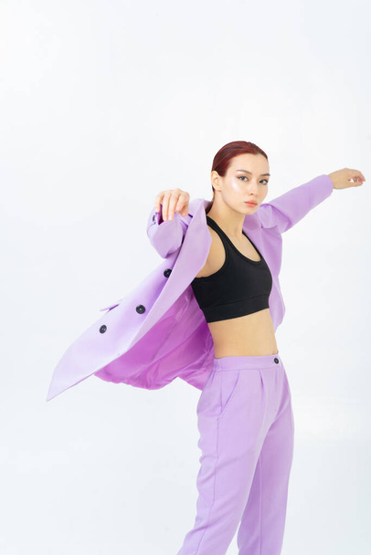 An Asian model poses in the studio in a trendy purple suit and a sporty black top. Red hair. Light background. - Foto, immagini