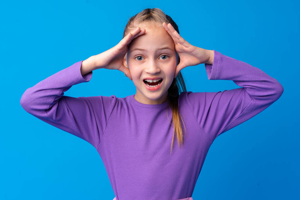 Shocked little girl looking with amazement on blue background - Foto, Imagen