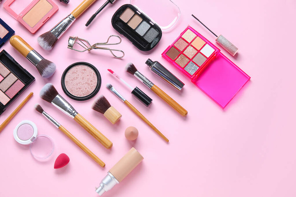 Szczotki do makijażu drewniane z kosmetykami dekoracyjnymi na różowym tle - Zdjęcie, obraz