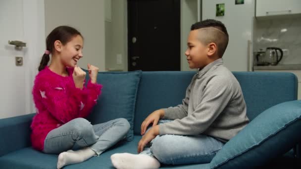 Multietnikowy chłopiec i dziewczyna przybijają piątkę, śmiejąc się razem w domu - Materiał filmowy, wideo