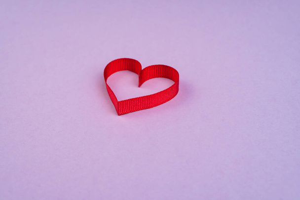 Vista superior Concepto de San Valentín con espacio para copiar. Corazón de cinta roja sobre fondo de papper morado - Foto, imagen