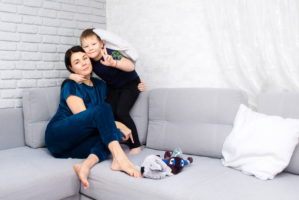 男の子の息子の母親は、ライフスタイルを抱きつく。ママは赤ん坊とソファに座っている。母の日、愛、家庭、父母、子女、概念。スペースのコピー - 写真・画像