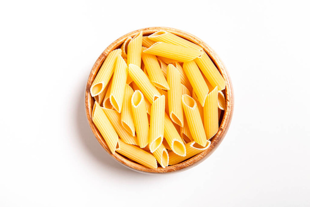 Uncooked pasta in wooden bowl on white background. - Valokuva, kuva