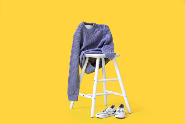 Chair with knitted sweater for child and shoes on color background - Photo, Image
