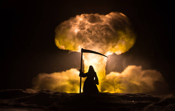 Πυρηνικός πόλεμος. Έκρηξη πυρηνικής βόμβας. Δημιουργική διακόσμηση σε σκούρο χρώμα. Η σιλουέτα του Χάρου που κοιτάζει ένα γιγάντιο μανιταρένιο σύννεφο ατομικής έκρηξης. Επιλεκτική εστίαση - Φωτογραφία, εικόνα
