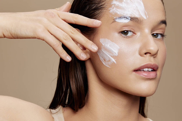 Frau mit Feuchtigkeitscreme auf den Wangen im Augenbereich Jugend- und Hautpflegekonzept - Foto, Bild