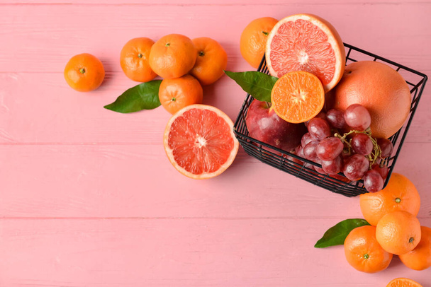 Basket with fresh juicy fruits on color wooden background - Φωτογραφία, εικόνα