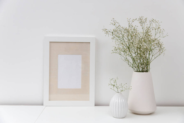 Blank canvas frame mockup. Artwork in interior design. View of modern scandinavian style interior with canvas for painting or poster on wall. Living room, commode with vases. Minimalism concept - Photo, image