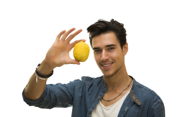 Smiling young man holding a fresh yellow lemonin his hand - Foto, immagini
