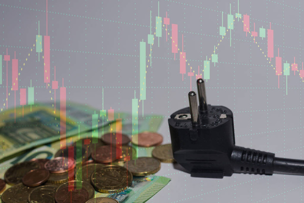 Energieverbrauch und Anstieg der Strompreise 100-Euro-Scheine und -Münzen mit einer Grafik im Hintergrund - Foto, Bild