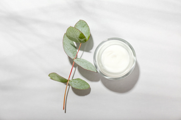 Jar with natural cosmetic cream and eucalyptus branch on white background - Foto, Imagem