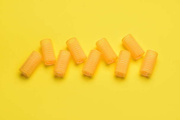 Hair curlers on yellow background - Фото, зображення