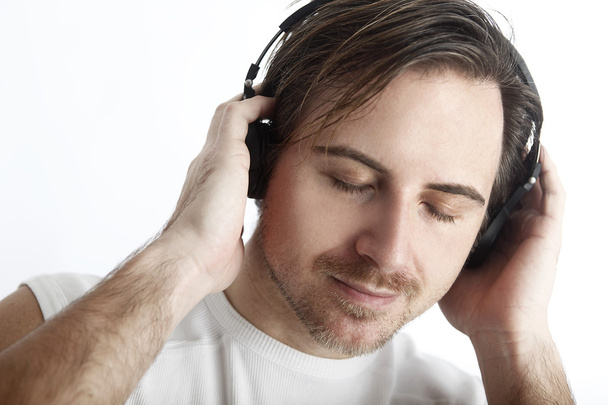 Attractive man with headphones in front of a white background en - Photo, Image