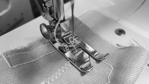 Sewing machine. Sewing machine foot on fabric. Steel needle with loop and pressed foot close-up. Black and white photo. - Zdjęcie, obraz