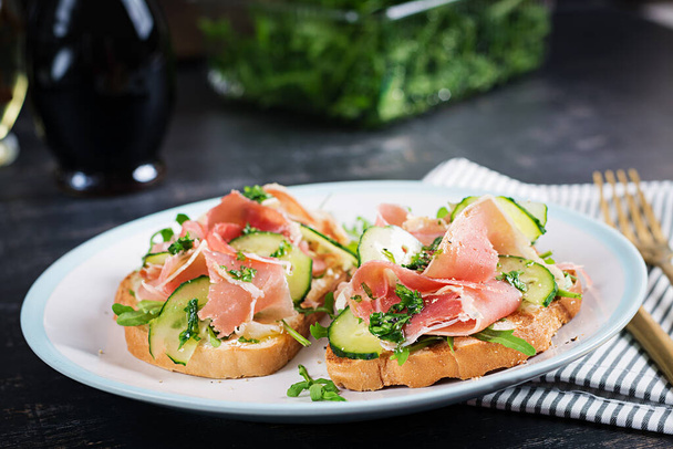 Breakfast or brunch.  Open sandwich with prosciutto or jamon on white plate. Mediterranean appetizer. - Foto, Bild