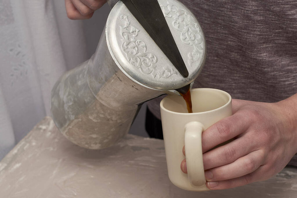 a man pours coffee into a mug from a geyser. High quality photo - Photo, Image