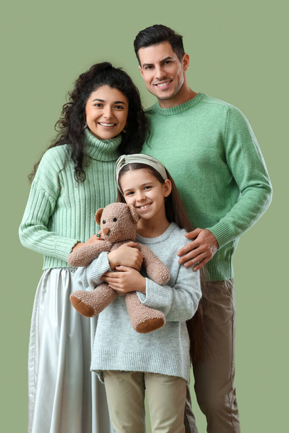 Szczęśliwi rodzice z córeczką w ciepłych swetrach na zielonym tle - Zdjęcie, obraz