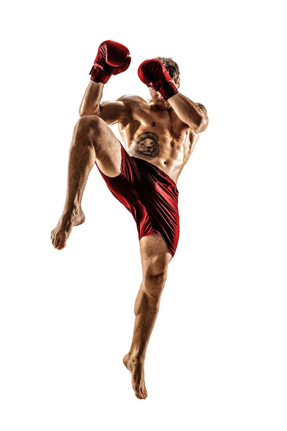 Full size of male kickboxer in red sportswear on white background. muscular athlete fighting - Фото, изображение
