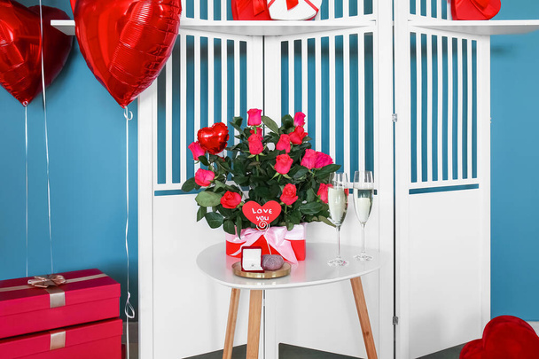 Коробка з трояндами, обручка та келихи шампанського на столі біля складного екрану в кімнаті, прикрашеній для Валентина. - Фото, зображення
