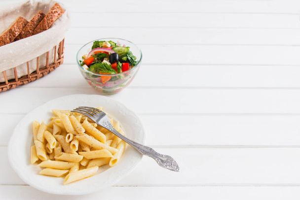 Cooked penne with useful vegetables salad white table. - Photo, Image