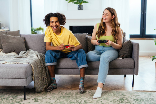 modern multiethnic unstereotyped couple playing videogames at home. Not stereotyped boyfriend and girlfriend living together. True love concepts - Zdjęcie, obraz