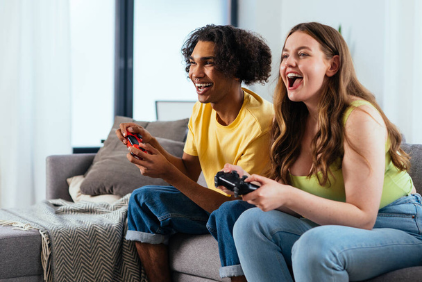 modern multiethnic unstereotyped couple playing videogames at home. Not stereotyped boyfriend and girlfriend living together. True love concepts - Фото, зображення