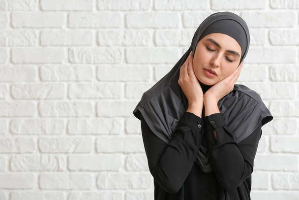 Beautiful Muslim woman on white brick background - Fotó, kép