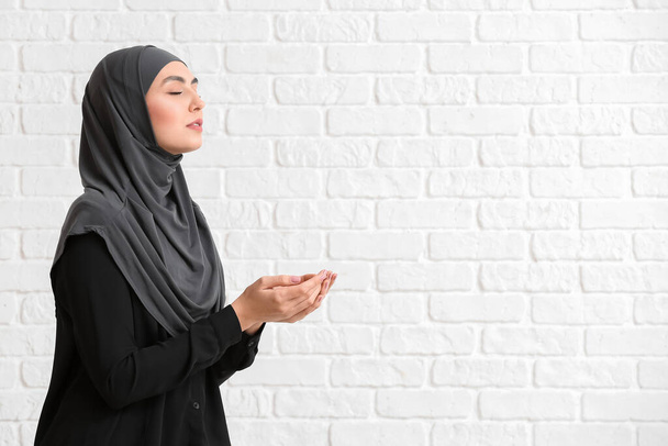 Muslim woman praying on brick background - Zdjęcie, obraz