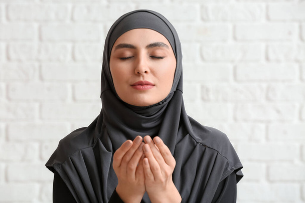 Muslim woman praying on brick background - Fotografie, Obrázek