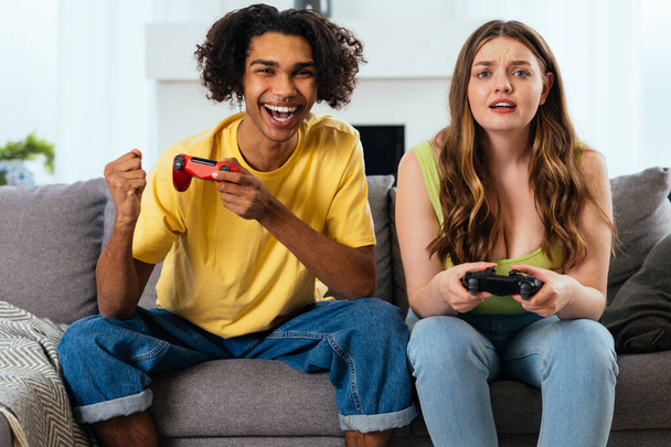 modern multiethnic unstereotyped couple playing videogames at home. Not stereotyped boyfriend and girlfriend living together. True love concepts - Photo, Image