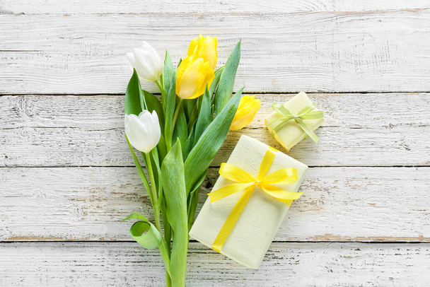 Composición con cajas de regalo y flores para la celebración del Día Internacional de la Mujer sobre fondo de madera clara - Foto, imagen